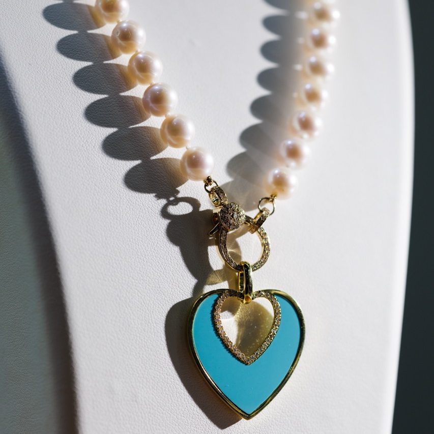 Elegant pearl necklace featuring a turquoise enamel heart pendant outlined with pavé diamonds and gold accents, photographed in soft natural light